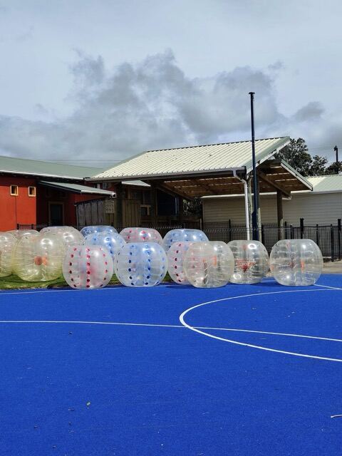 Lineup of inflatable bumper balls for hire on a blue court