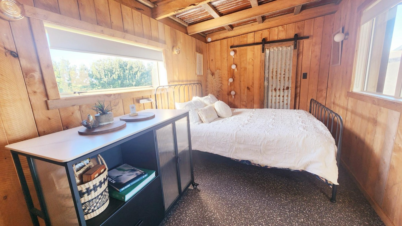 Queen bedroom with timber walls and soft linen