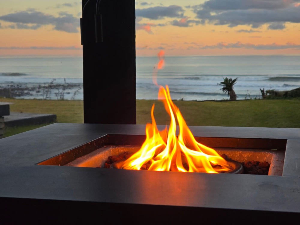 Gas fire table burning on the covered deck with the sea beyond
