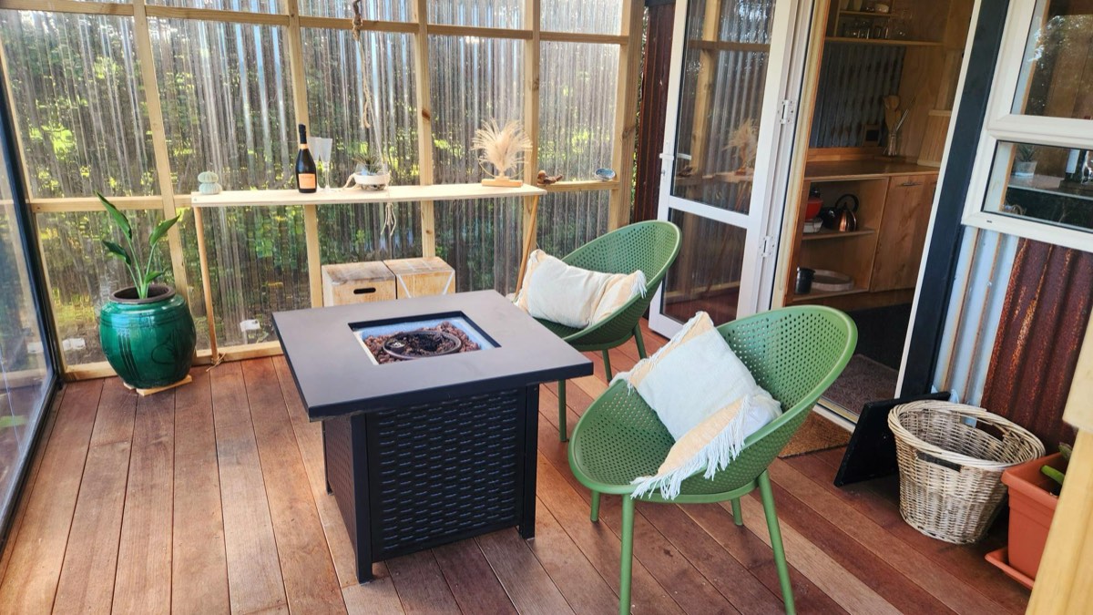 Covered deck with gas fire table and sage-green chairs