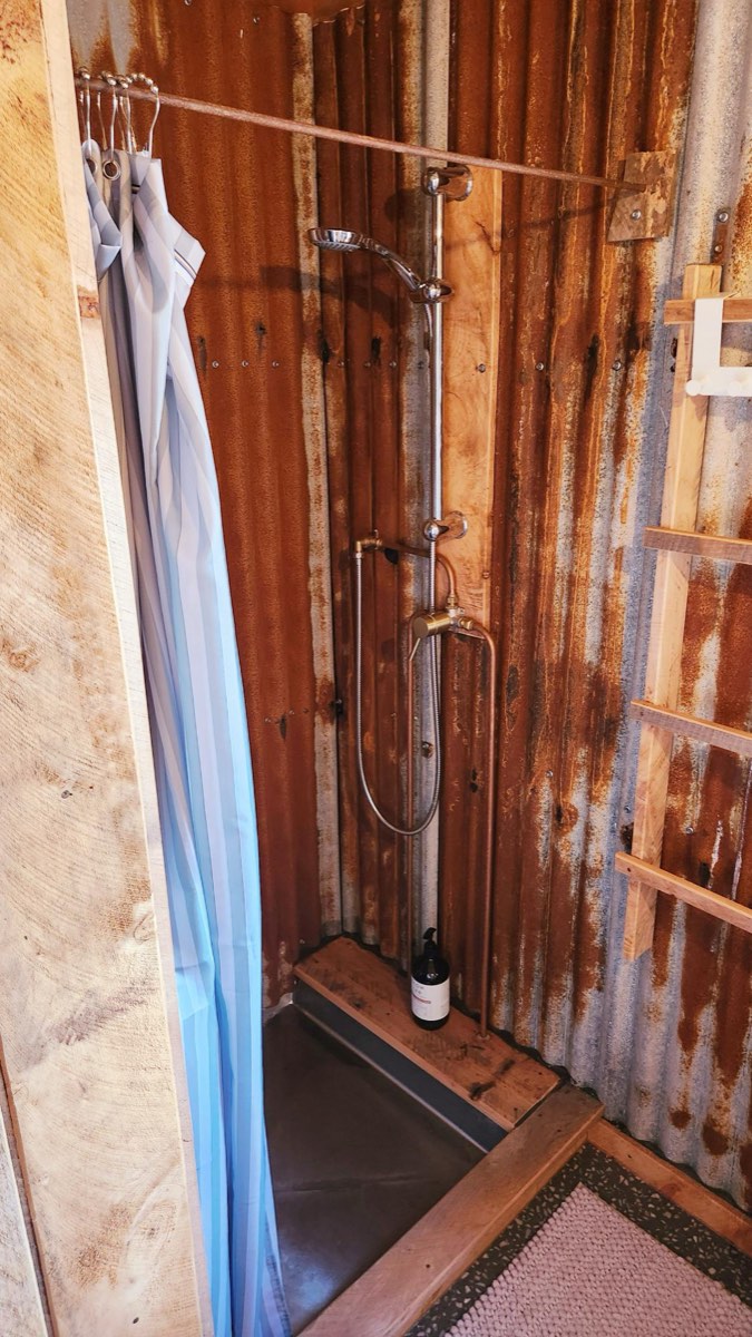 Indoor shower lined with timber and corrugated iron